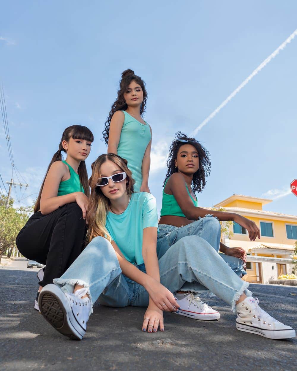 Group of diverse teenage girls in casual fashion posing confidently on city street.