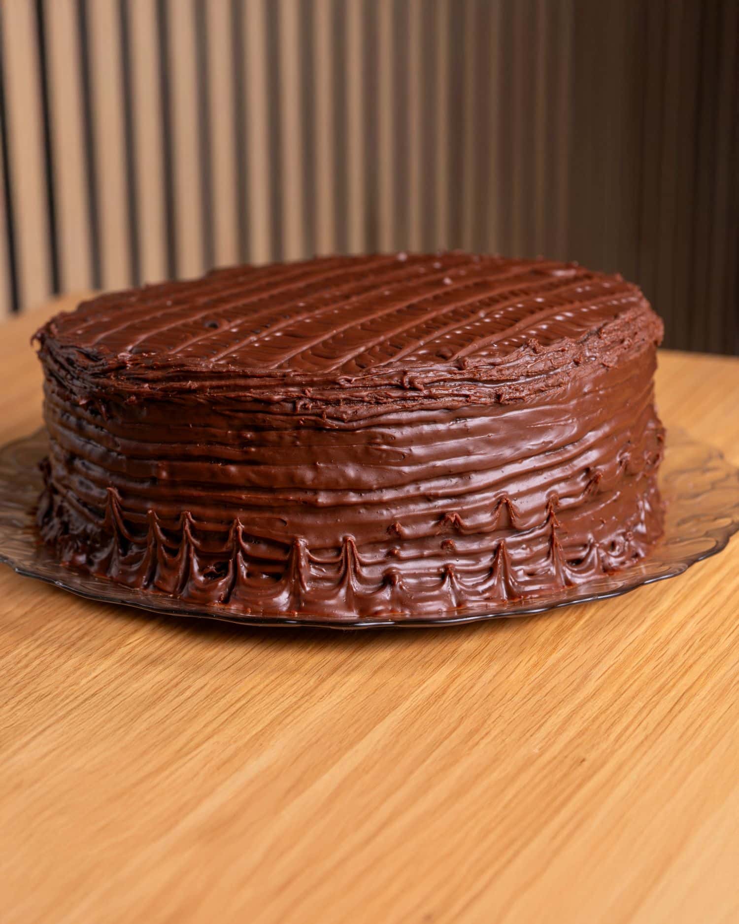 Rich chocolate cake with creamy frosting on a wooden table