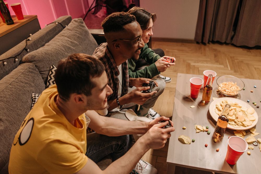 Group of friends playing video games and enjoying snacks indoors.