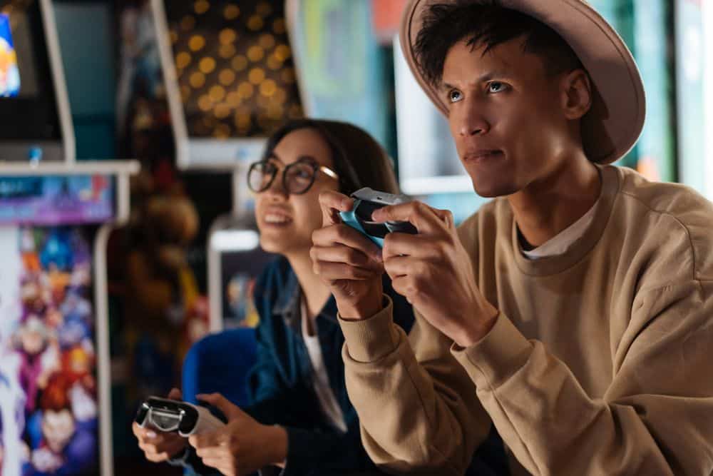 Two adults enjoying an immersive gaming session at an arcade, focusing intently on their game controllers.