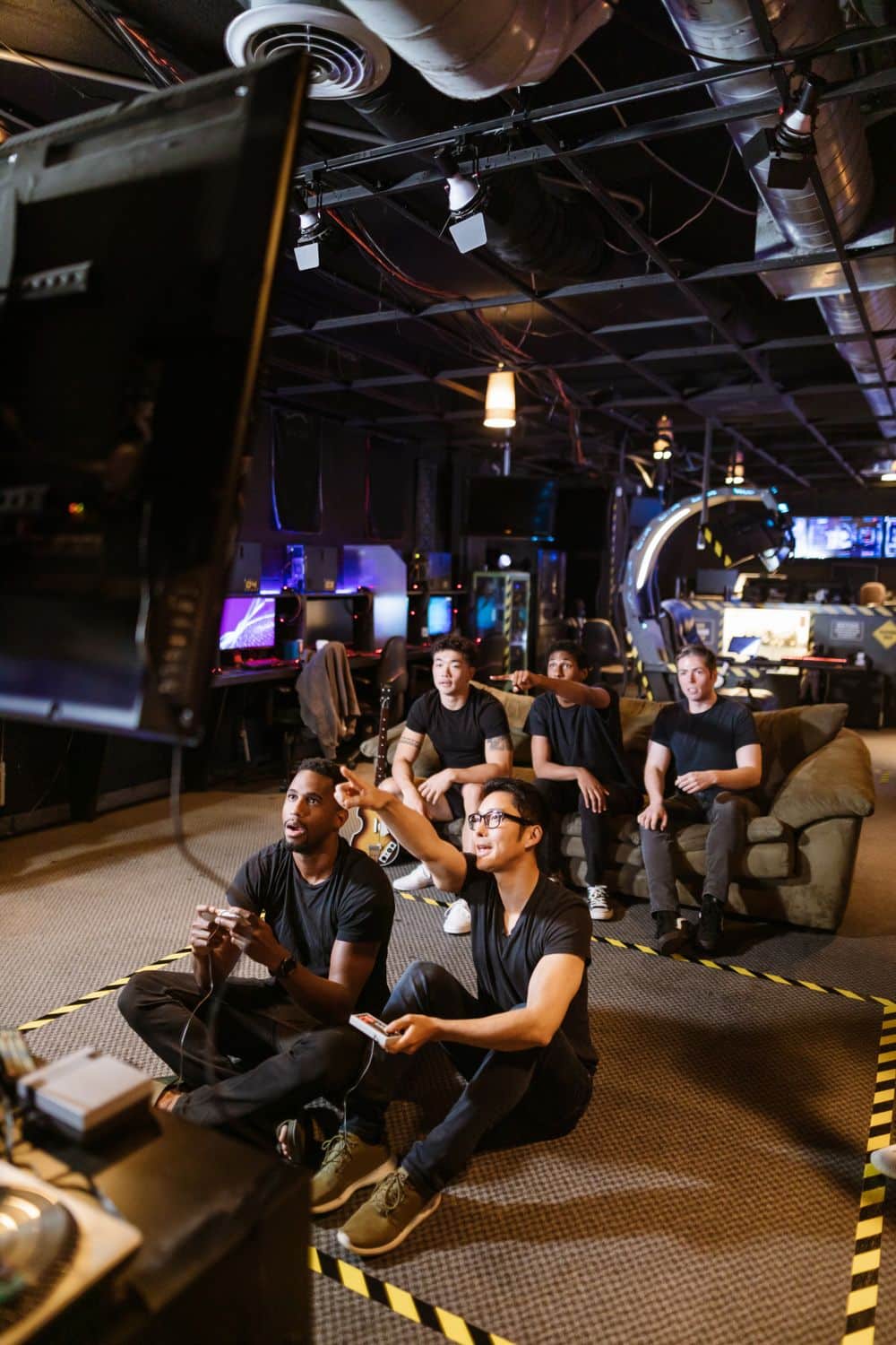 A diverse group of friends playing video games in a modern arcade setting.