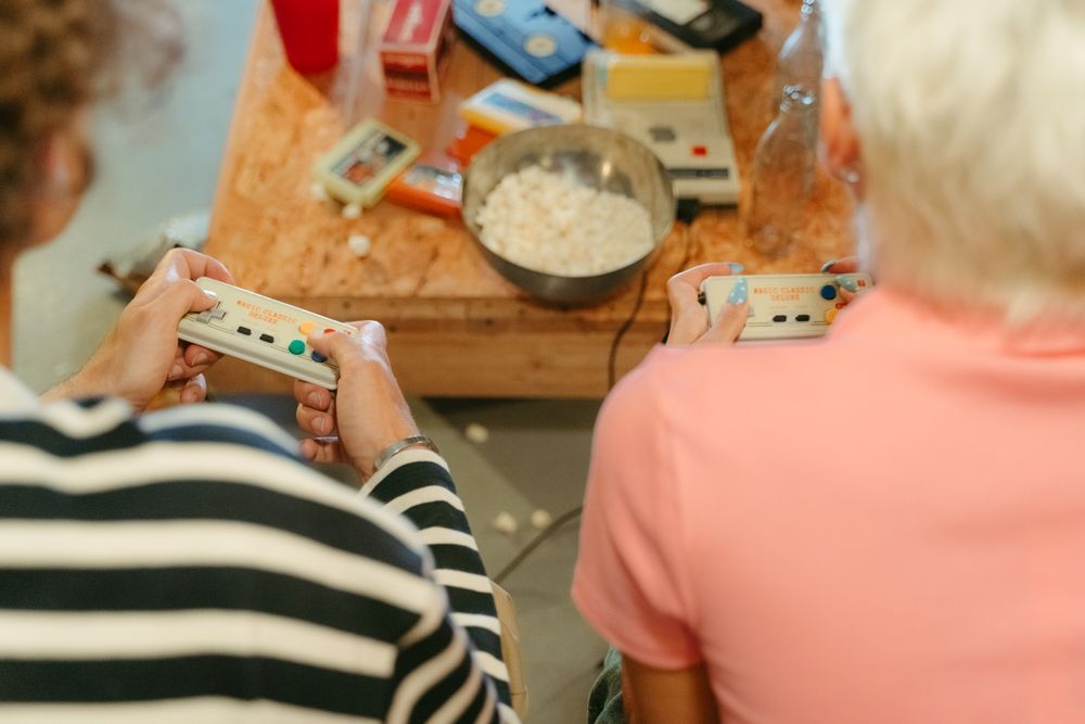 Two teenagers play video games together with snacks, creating a fun indoor atmosphere.