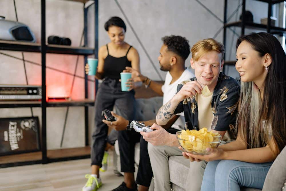 A group of diverse friends enjoying video games and snacks at home, creating a fun and relaxed atmosphere.