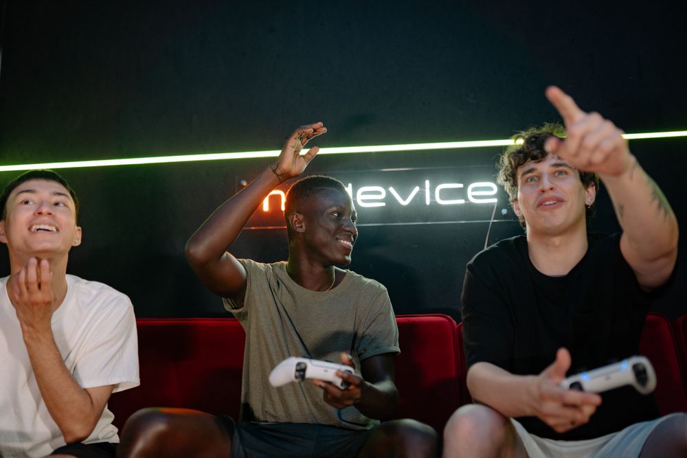 Three young men enthusiastically playing video games together, using wireless controllers indoors.