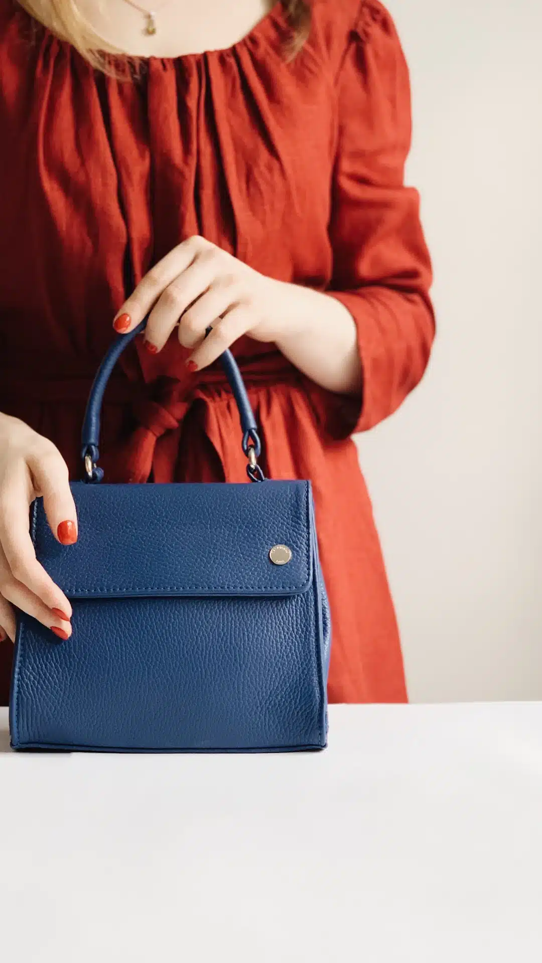 woman holding blue leather handbag